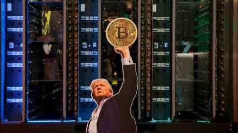 A cut-out of US President Donald Trump holding a bitcoin is displayed on a group of servers