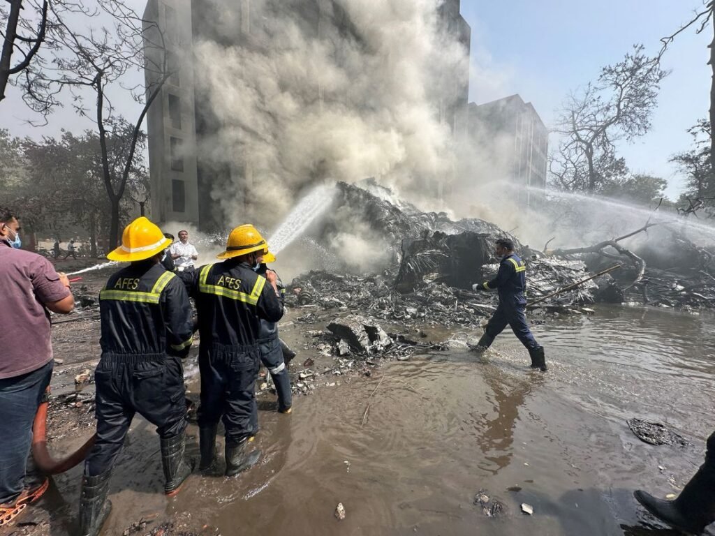 Rescue team members work as smoke rises at the site where an Air India plane crashed in Ahmedabad, India.
