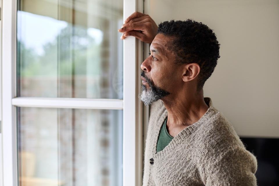 A man looking forlorn as he looks outside. (Getty Images)
