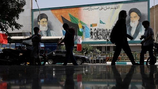 People walk next to a mural with a picture of Iran's Supreme Leader, Ayatollah Ali Khamenei, on a street, early hours of ceasefire, in Tehran, Iran, on June 24.(Reuters)