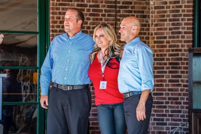 Stormy Daniels stands between two men for a photo