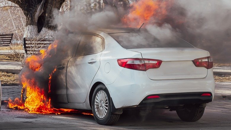 A white passenger car in flames.
