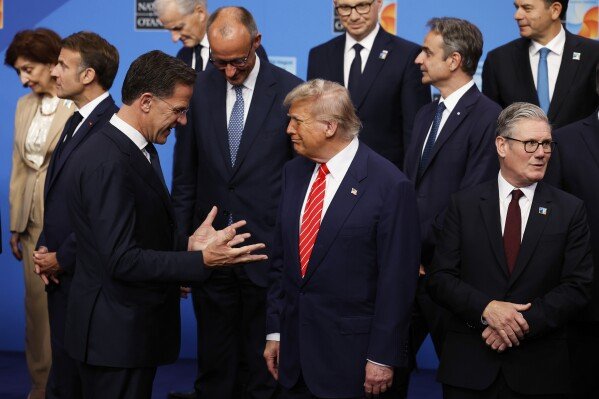 President Donald Trump, center, speaks with NATO Secretary General Mark Rutte, left, during a group photo of NATO heads of state and government at the NATO summit in The Hague, Netherlands, Wednesday, June 25, 2025. (AP Photo/Geert Vanden Wijngaert)