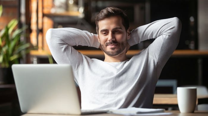 A man looks at his computer with satisfaction.
