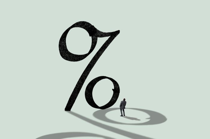 A person looking up a a big percent sign.