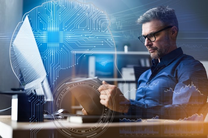 A person looking at a laptop PC with a digital circuit image superimposed.