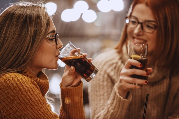 Two people sipping sodas.