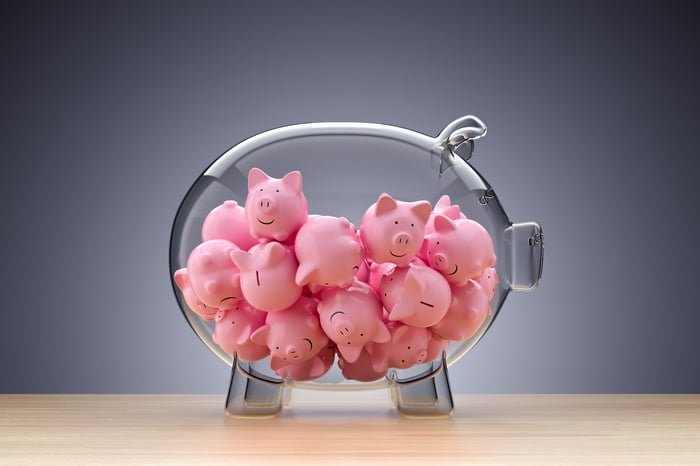 Tiny pink piggy banks inside a larger, clear piggy bank.