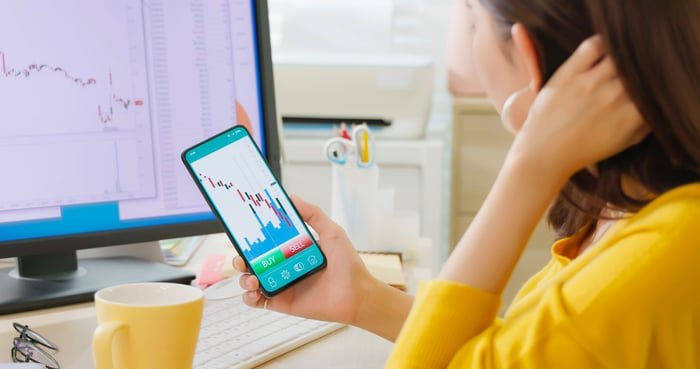Person looking at a falling stock chart on their phone.