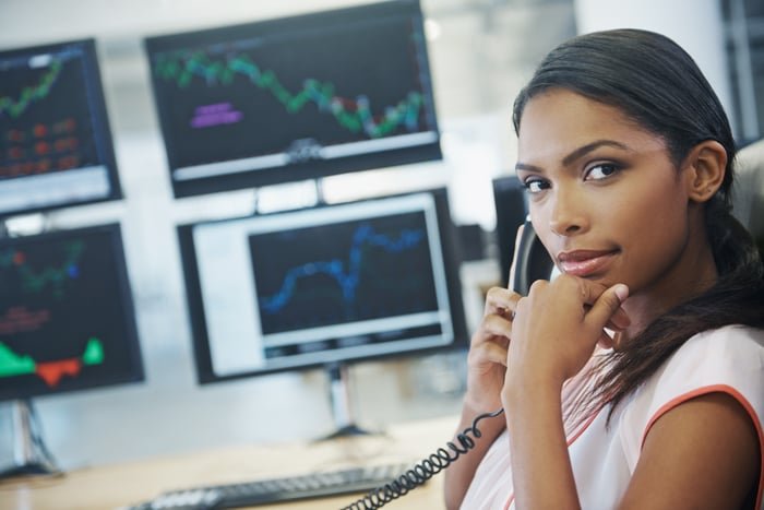 An investor talks on the phone while sitting in front of trading screens.