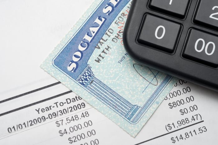 A Social Security card on a financial statement with a calculator on top of it.