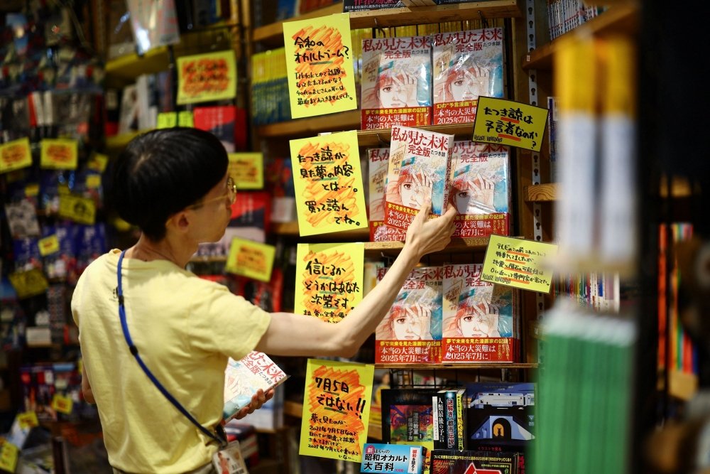 A member of staff places the comic book titled ‘The Future I saw’, authored by manga artist Ryo Tatsuki, on the shelf at Village Vanguard book store in Tokyo June 30, 2025. — Reuters pic