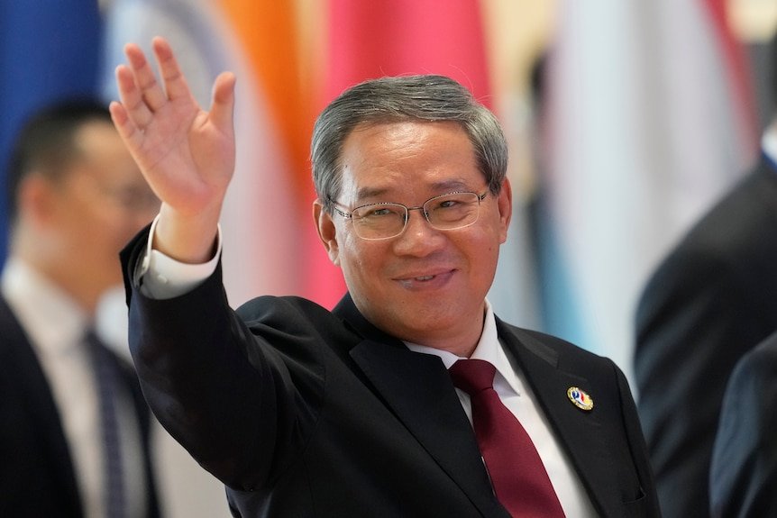 Li Qiang in a black suit, waving.