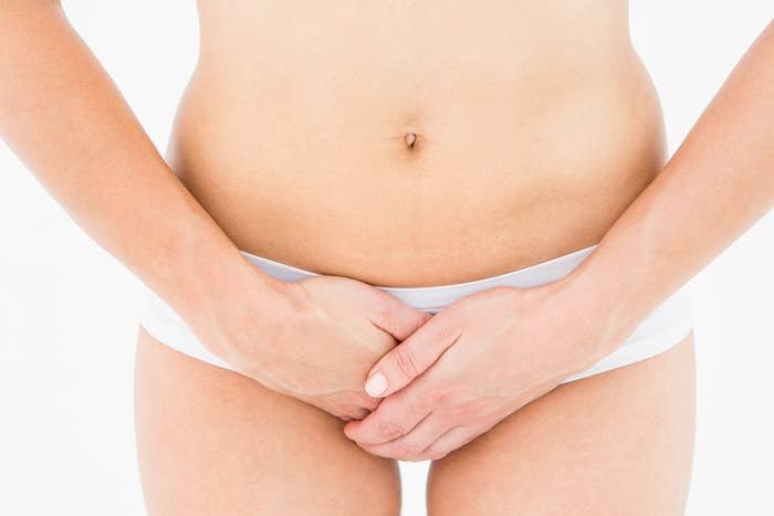 Person in underwear covering lower abdomen with hands