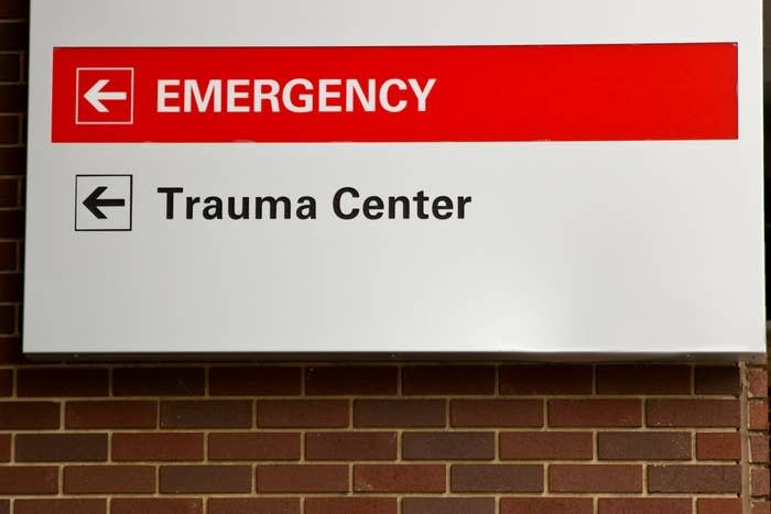 Sign on a brick wall pointing left to "Trauma Center" and straight ahead to "Emergency."