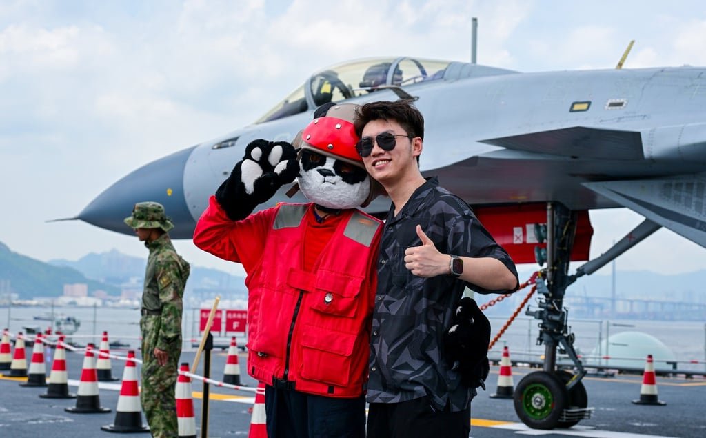A fighter jet is the backdrop for a visitor’s photo with a crew member. Photo: Xinhua