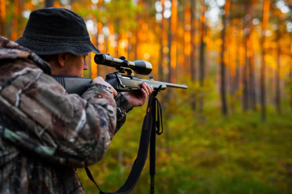 A man pointing a hunting gun in a scenic forest