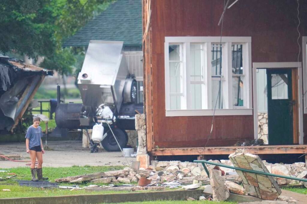 A person looks at damage to the main building at Camp Mystic along the banks of the Guadalupe River.