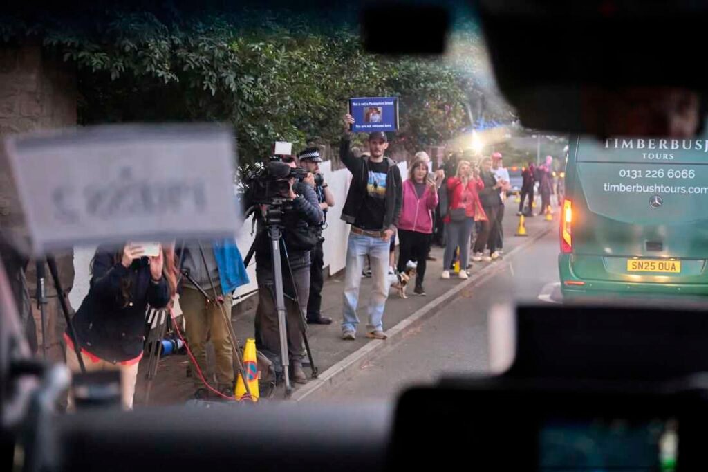 A man seen through the windshield of a moving vehicle holds up a sign reading: "This is not a paedophile island. You are not welcome here," as the motorcade of President Trump arrives at the golf course in Turnberry, Scotland, on Friday.