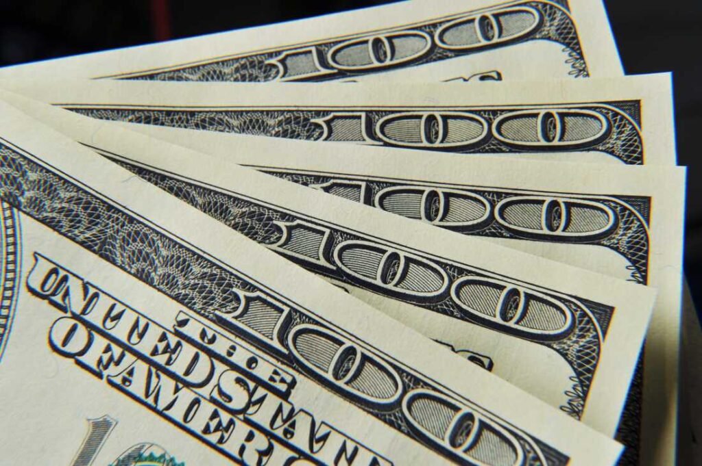This photo shows the top-right corners of five $100 bills spread in a fanlike arrangement.