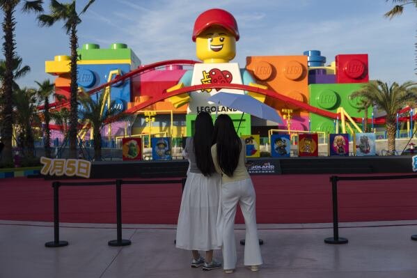 Women look at a giant Lego character at Legoland Shanghai a day before it opens to the public in Shanghai, China, Friday, July 4, 2025. (AP Photo/Ng Han Guan)