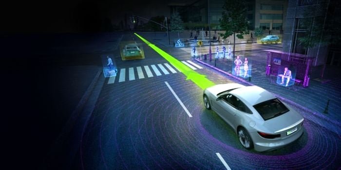 Driverless vehicle on a city street with pedestrians on sidewalks.