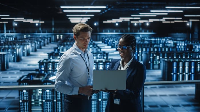 Two engineers stand in front of a data center.