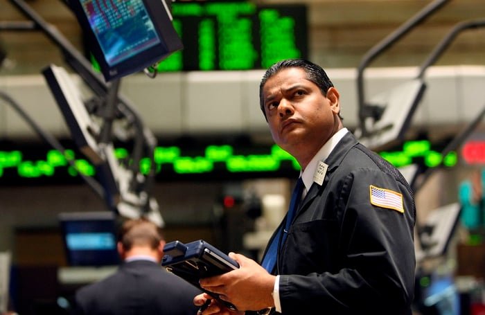 A New York Stock exchange floor trader looking up in bewilderment at a computer monitor.