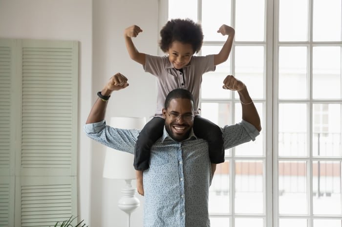 A parent and a child making muscles together.