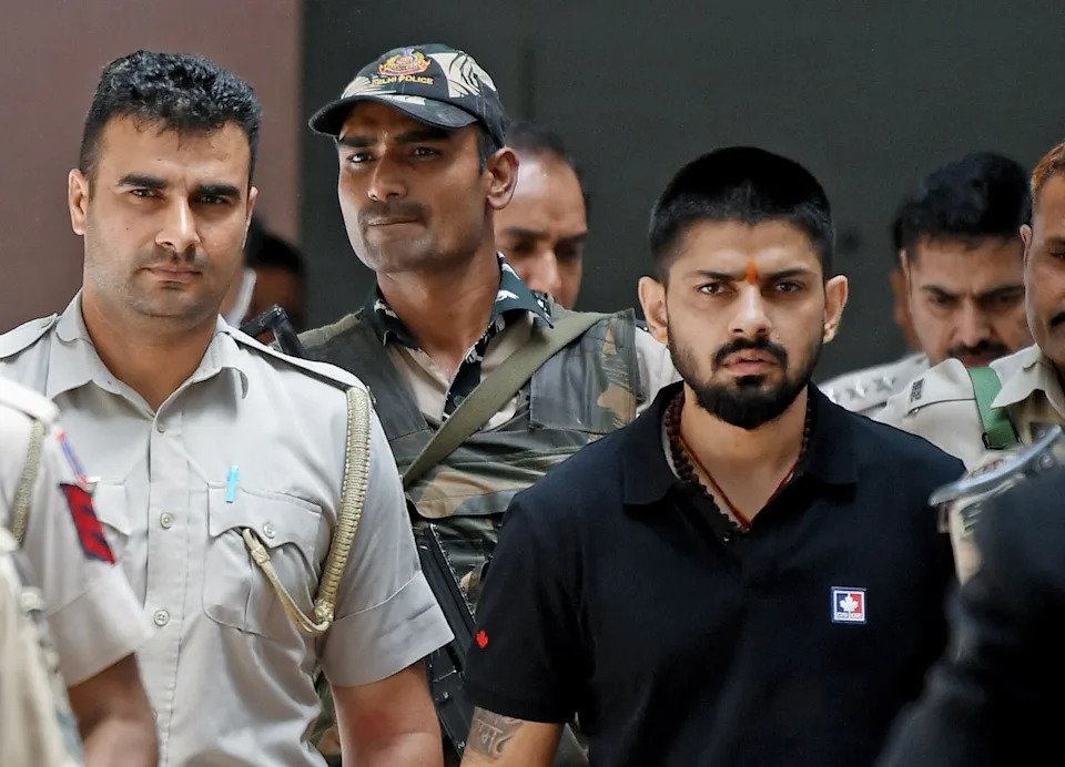Police officers escort Lawrence Bishnoi, right, inside a courthouse in New Delhi, India, on April 18, 2023.