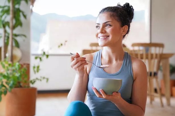 woman eating a parfait for breakfast at home and smiling