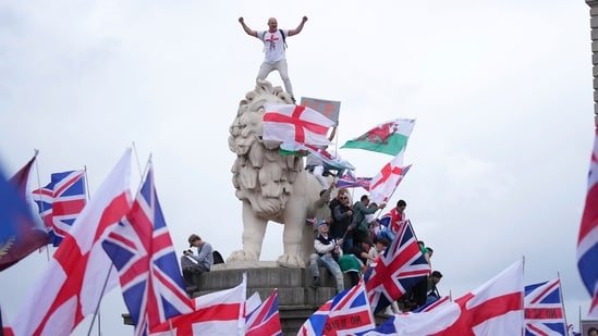A demonstrator stands on the head of one of the lions of Westminster Bridge during a Tommy Robinson-led Unite the Kingdom march and rally in London, Saturday, Sept. 13, 2025. (AP)