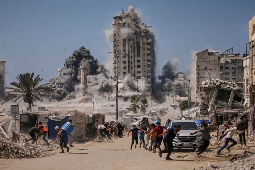 Palestinians run for cover during an Israeli airstrike on a high-rise building in Gaza City, Friday, Sept. 5, 2025, after the Israeli army issued a warning.