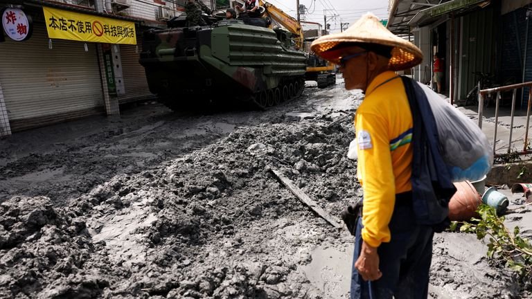 A man stands near a military vehicle on a road filled with mud brought by flooding in Hualien, Taiwan. Pic: Reuters
