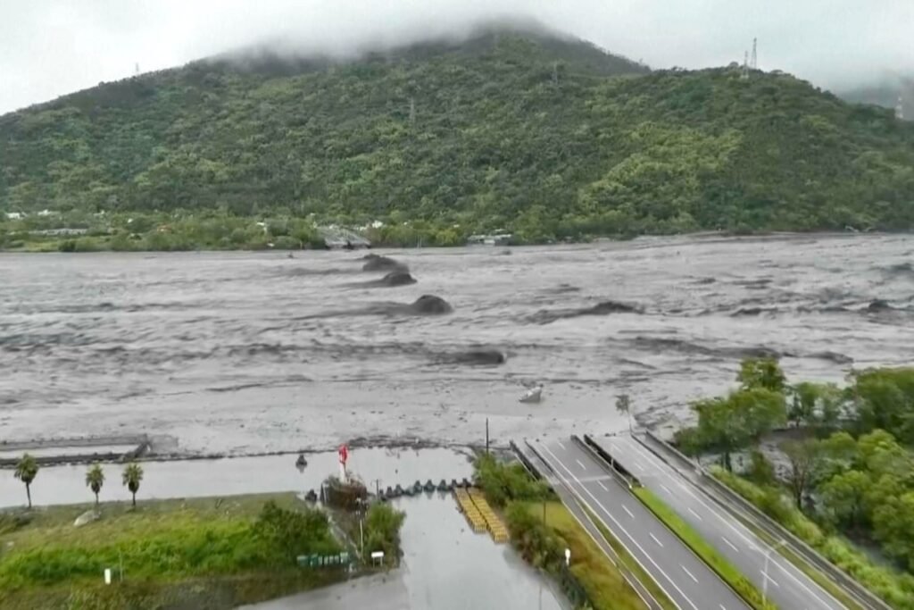A bridge is partially submerged by water, with a mountain shown in the background.