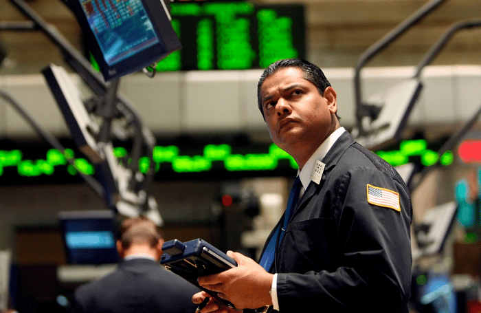 A New York Stock Exchange floor trader looking up in disbelief at a computer monitor.