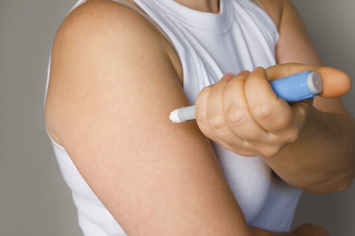 A person using an injector pen on their arm.