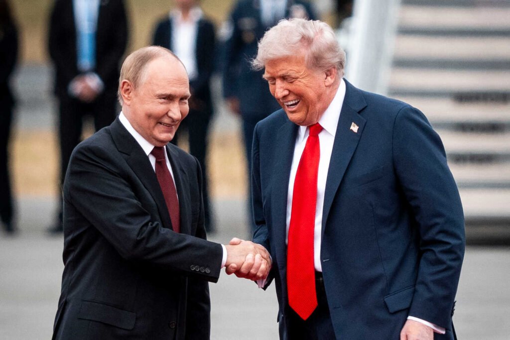 President Trump and President Vladimir V. Putin are shaking hands and laughing on a red carpet.