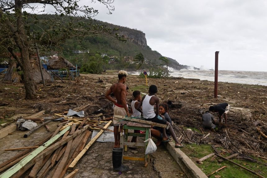 Residents stand on a beach covered with debris in the aftermath of Hurricane Melissa, in Santiago, Cuba, on Wednesday.