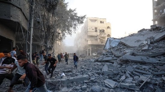 People run for cover following an Israeli strike that targeted a building in the Bureij camp for Palestinian refugees in the central Gaza Strip on October 19, 2025.(AFP)