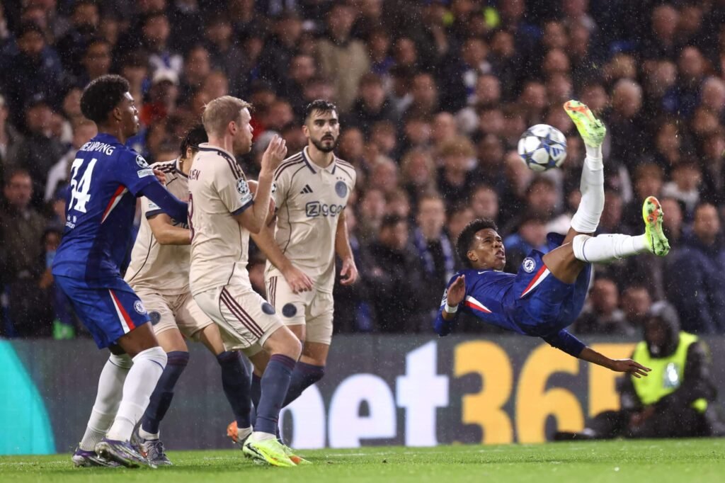 An airborne Estevao connects with an overhead kick as a crowd of Ajax players attempt to react to his shot