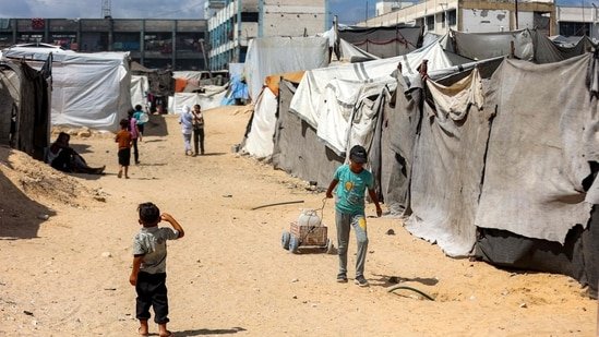 A child pulls a cart loaded with water containers past tents at a make-shift camp for people displaced by conflict in Khan Yunis in the southern Gaza Strip.(AFP)