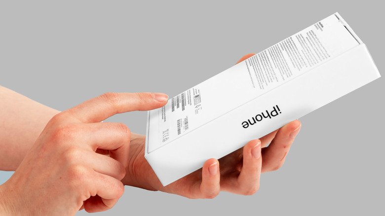 A hand looking at the back of an iPhone box.