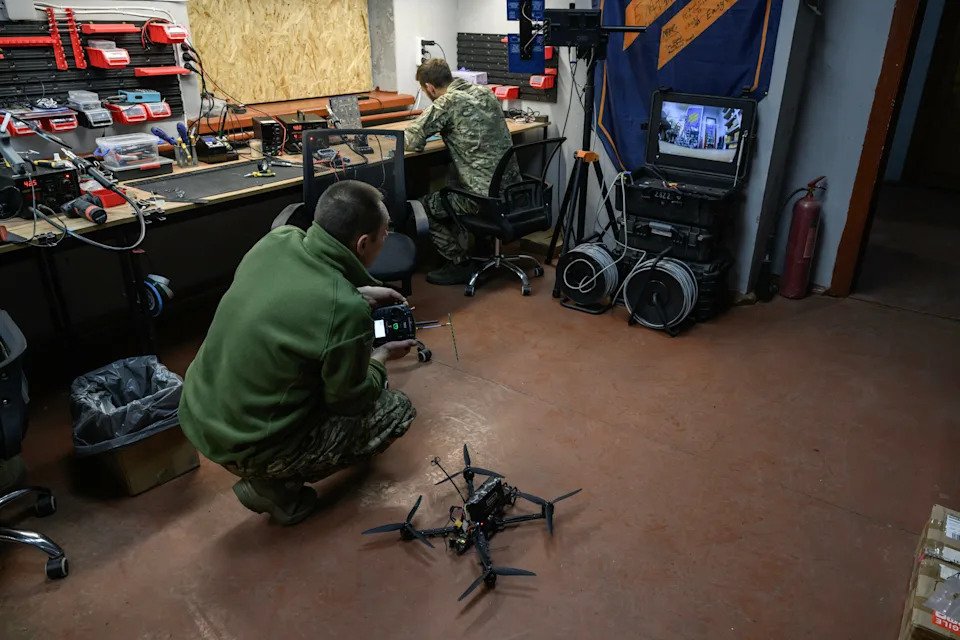 A Ukrainian soldier crouches with a remote next to a quadcopter used to destroy other drones.