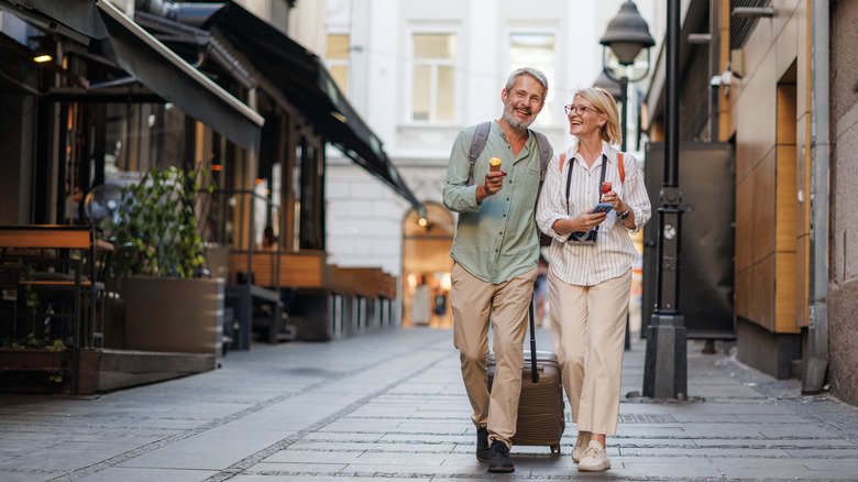 an elderly couple walks down a street in a European city