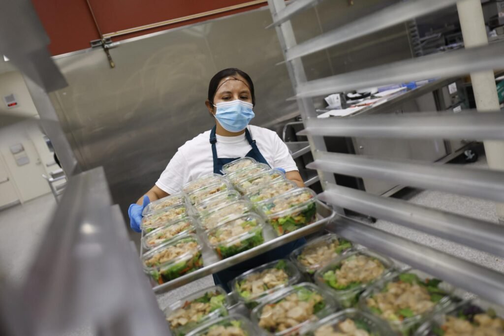 A person holds a tray of clear containers with food.